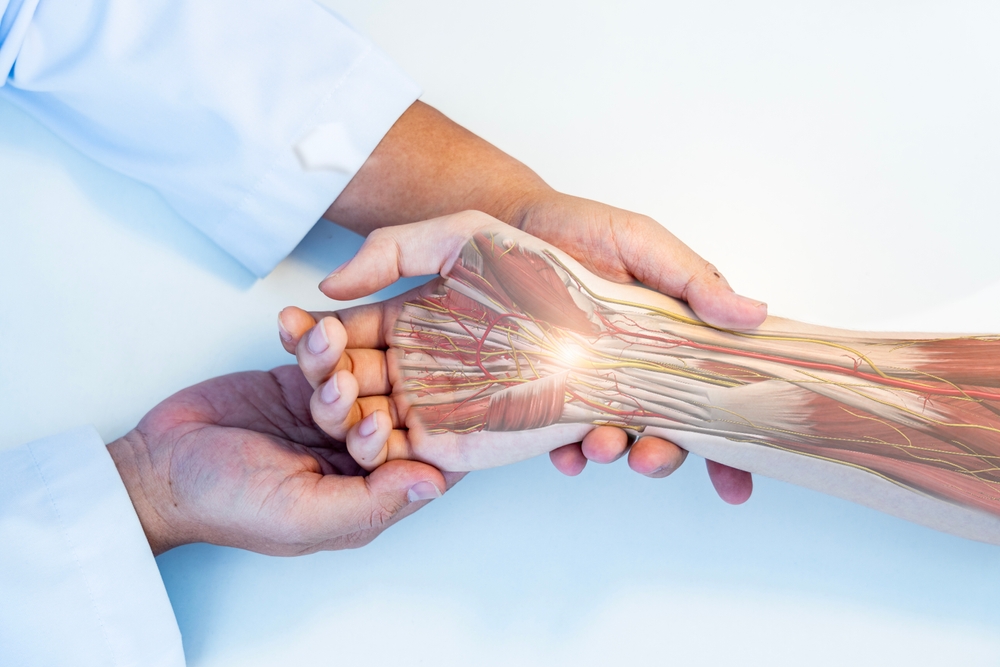 TheOrthopedicDoctorOrSurgeonInUniformExaminedThePatient - Dr Leena Jain Medical professional holding a forearm with a translucent anatomy overlay showing muscles and nerves around the wrist, with a bright glow at the center of the forearm edge of the hand side